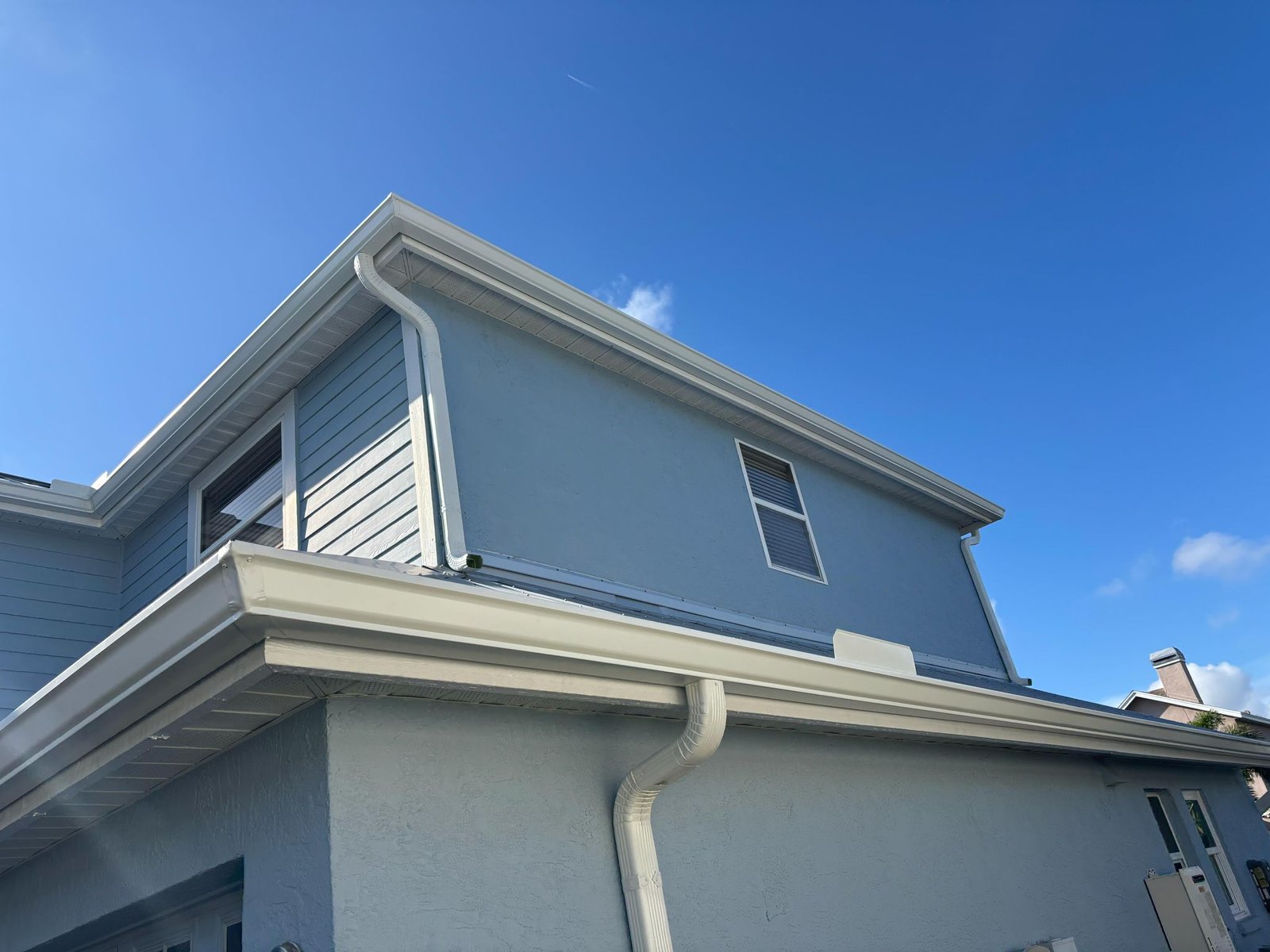 Professional white gutter installation and cleaning on a residential property